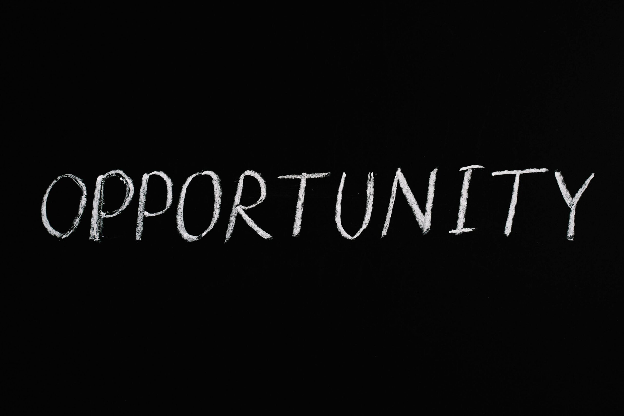 Word 'Opportunity' written in chalk on a black chalkboard, symbolizing new possibilities.