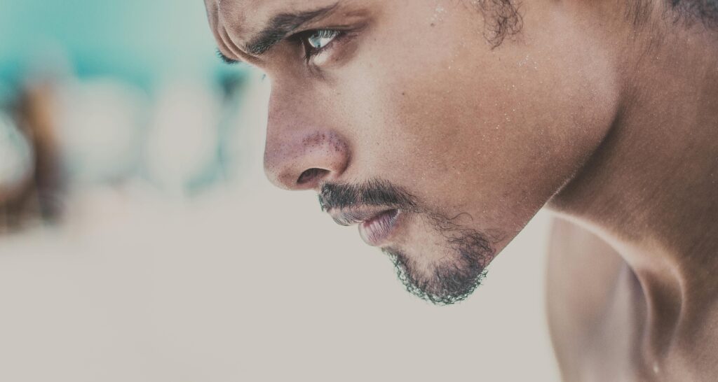 A close-up side view of a young man with a serious and focused expression.