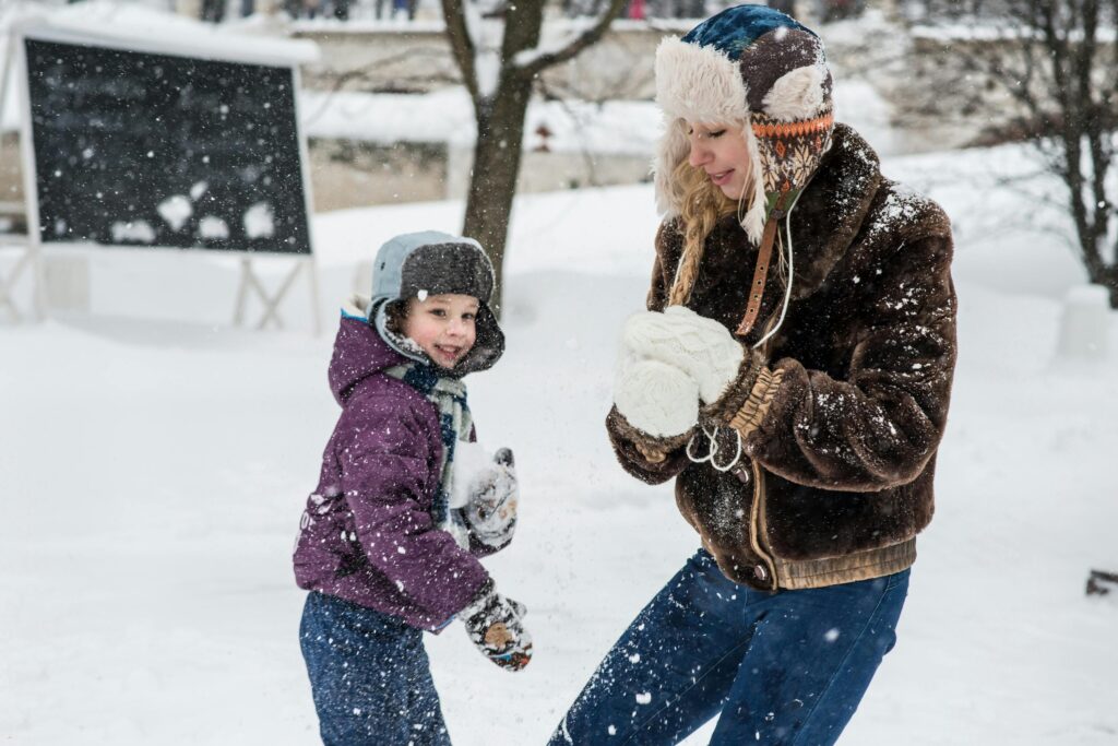 Mother and son enjoy a playful snowball fight, embracing the winter wonderland.