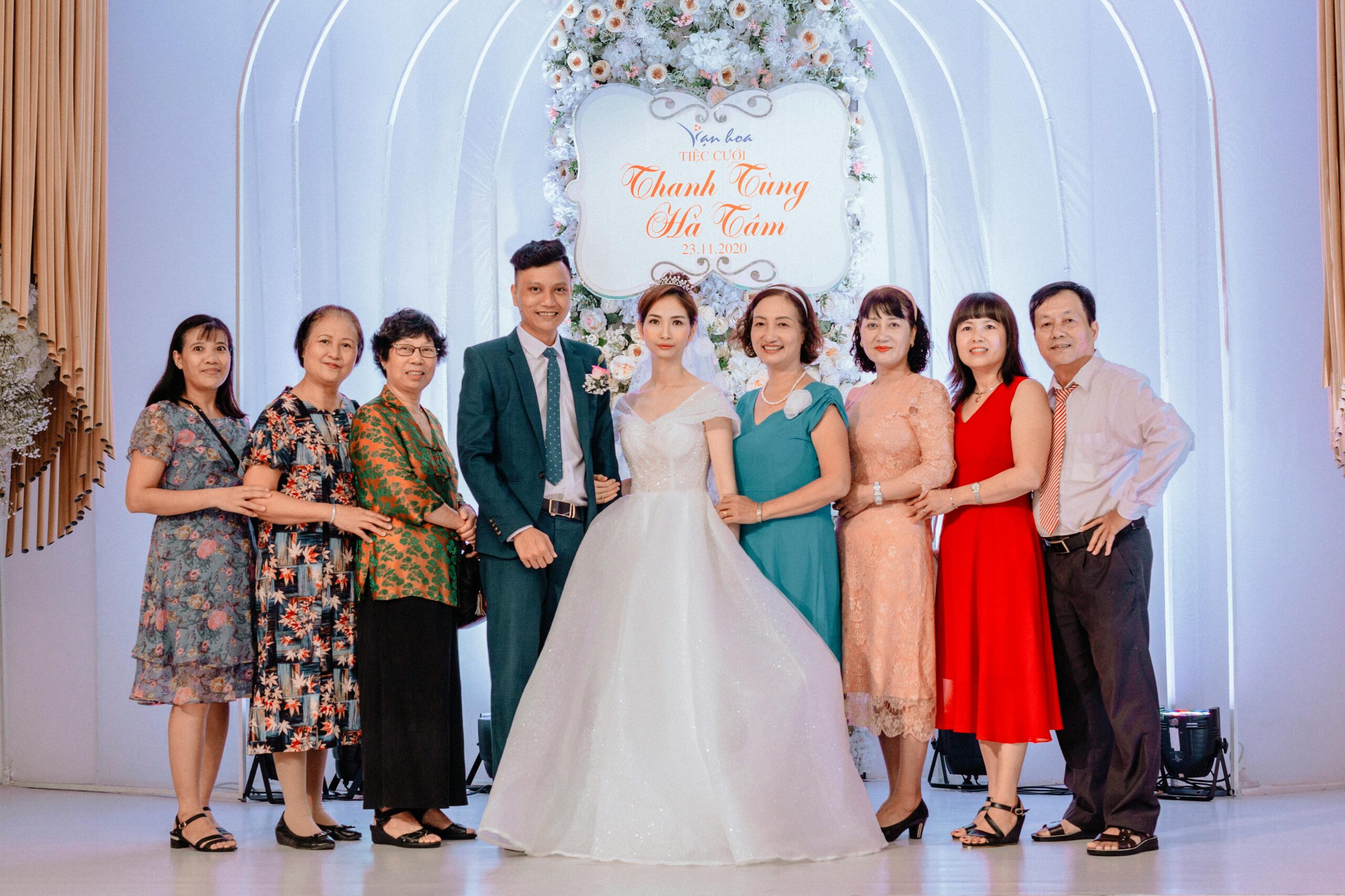 A happy family poses with the bride and groom at a vibrant wedding celebration.
