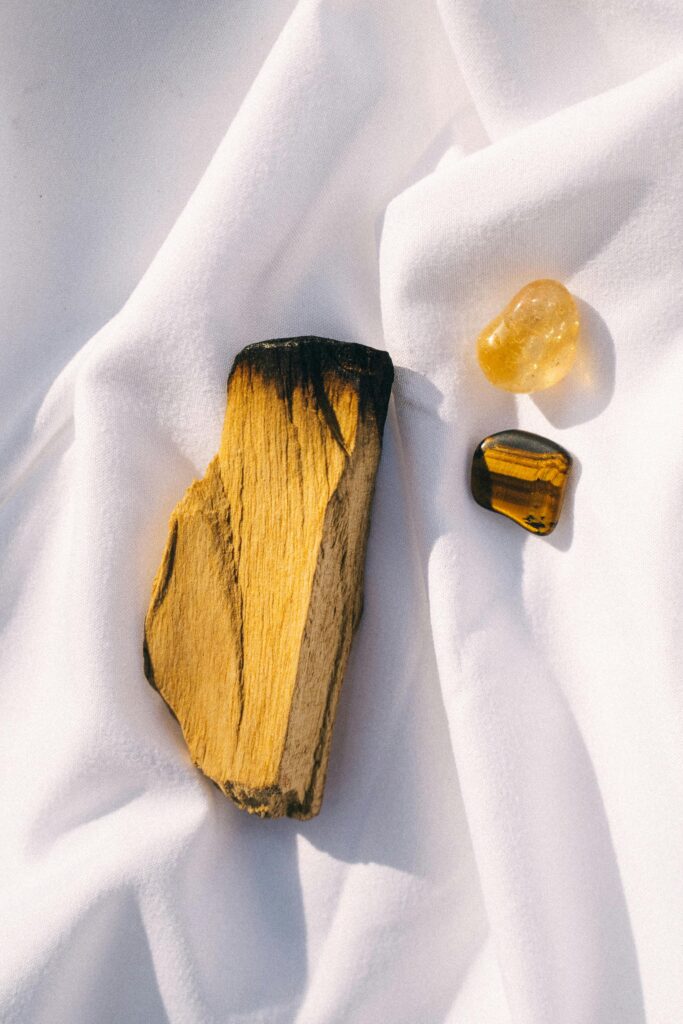 Arrangement of palo santo and crystals on white fabric for smudging rituals.
